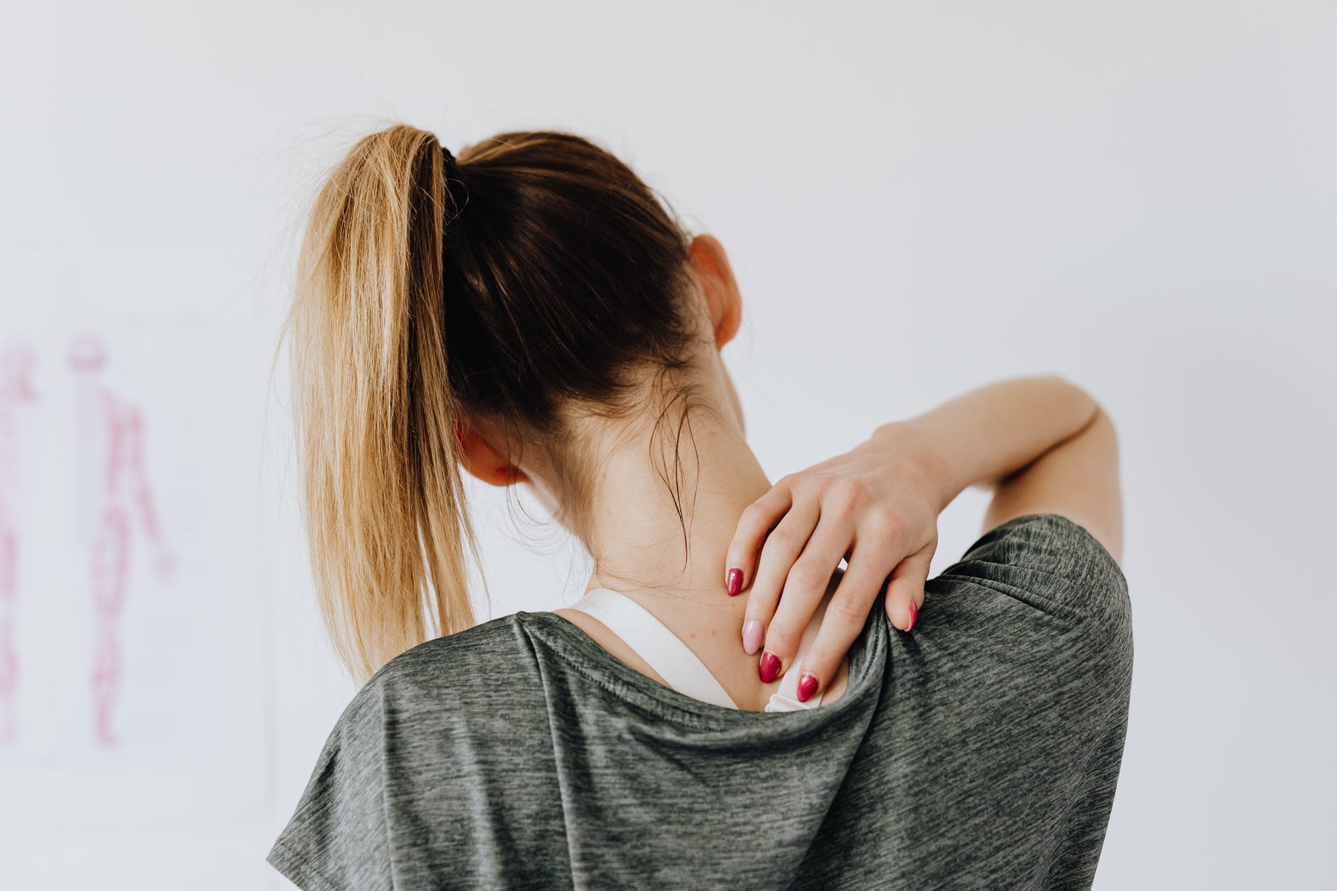 unrecognizable woman showing pain spot on back in doctor office
